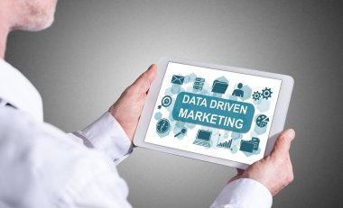 Elinde veri güdümlü pazarlama kavramını gösteren bir tablet tutan adam
