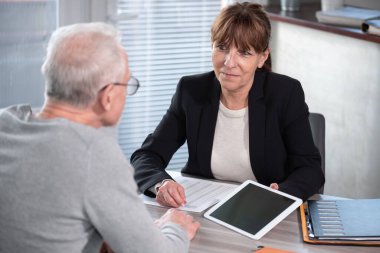 Kadın mali danışman müşterisine dijital tablet hakkında bilgi veriyor