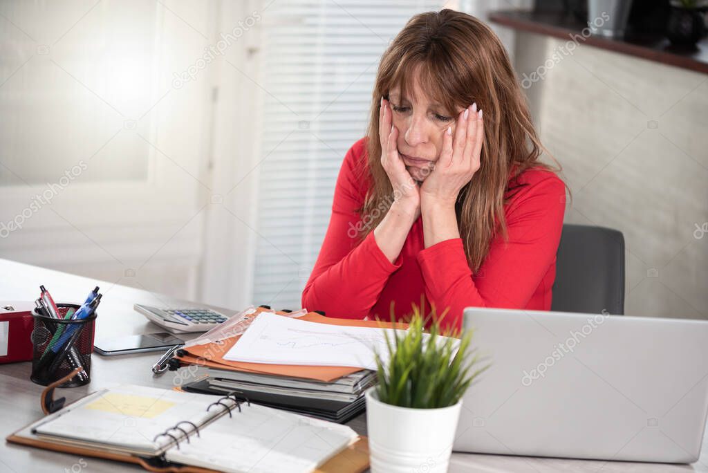 Overworked and exhausted businesswoman sitting at workplace