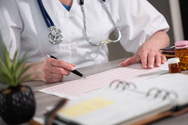 Kadın kardiyolog muayenehanede ecg grafiğini inceliyor.