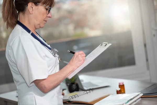 Γυναίκα Γιατρός Κρατώντας Σημειώσεις Σχετικά Πρόχειρο Στο Ιατρικό Γραφείο — Φωτογραφία Αρχείου