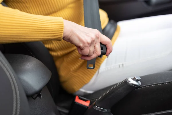 Woman fastening seat belt in car