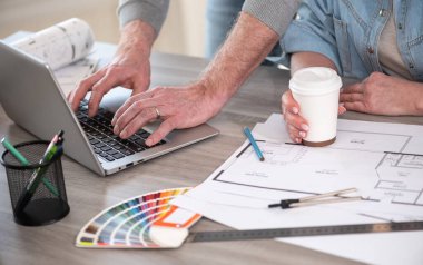 Yeni inşaat projesinde çalışan ve dizüstü bilgisayar kullanan mimarlar