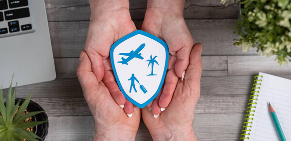 Concept of travel insurance with paper shield in hands