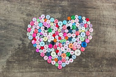 Ahşap arka plan üzerinde kalp şeklinde kullanılan düğmeleri topluluğu