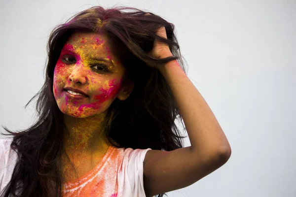 Portrait of a beautiful girl full of colored powder all over the body. Young girl plays with colors on the occasion of Holi. Concept for Indian festival Holi. Blank space available for written text.