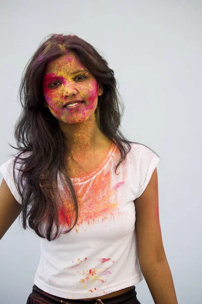 Portrait of a beautiful girl full of colored powder all over the body. Young girl plays with colors on the occasion of Holi. Concept for Indian festival Holi. Blank space available for written text.