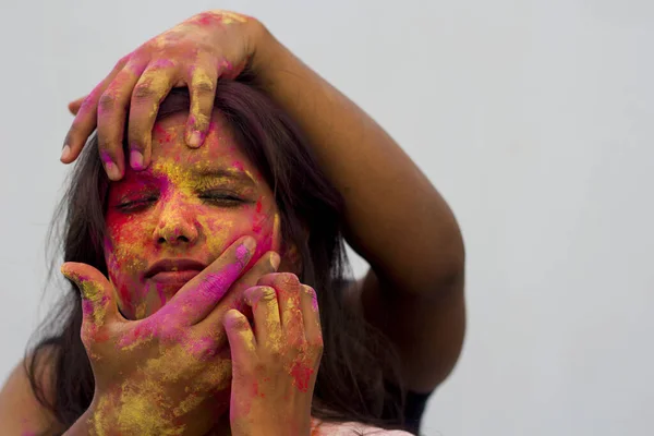 Portrait of a beautiful girl full of colored powder all over the body. Young girl plays with colors on the occasion of Holi. Concept for Indian festival Holi. Blank space available for written text.