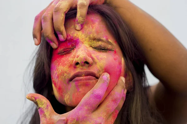 Portrait of a beautiful girl full of colored powder all over the body. Young girl plays with colors on the occasion of Holi. Concept for Indian festival Holi. Blank space available for written text.