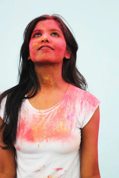 Portrait of a beautiful girl full of colored powder all over the body. Young girl plays with colors on the occasion of Holi. Concept for Indian festival Holi. Blank space available for written text.