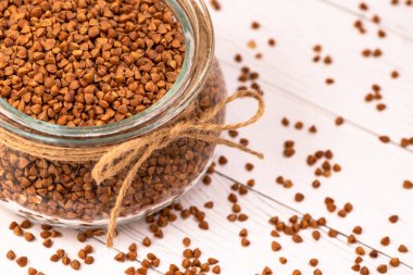 Cam bir kavanozdaki karabuğday kablosuyla yakın plan ve beyaz ahşap bir masaya dağılmış..