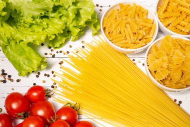 Spagetti, domates, şifalı otlar, biberler masaya saçıldı, çeşitli makarna çeşitleri beyaz cam tabaklara döküldü..