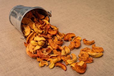 Küçük bir kovadan çarşaf örtüsüne saçılmış kurutulmuş elmaların yakın çekimi..