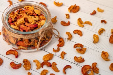 Kavanozda yakın planda kurutulmuş elmalar jüt kablosuyla birlikte beyaz ahşap bir masaya saçılmış..