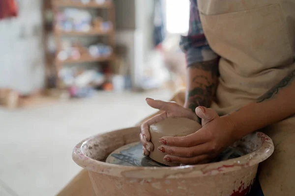 Close-up view of woman hands working on pottery wheel and making clay pot. Hands sculpts a cup from clay pot. Workshop on modeling on the potter\'s wheel.