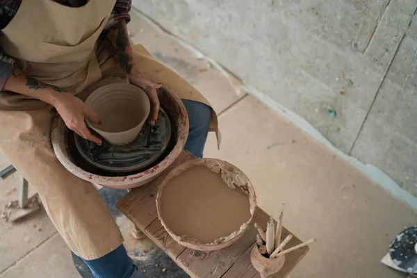 Close-up view of woman hands working on pottery wheel and making clay pot. Hands sculpts a cup from clay pot. Workshop on modeling on the potter\'s wheel.