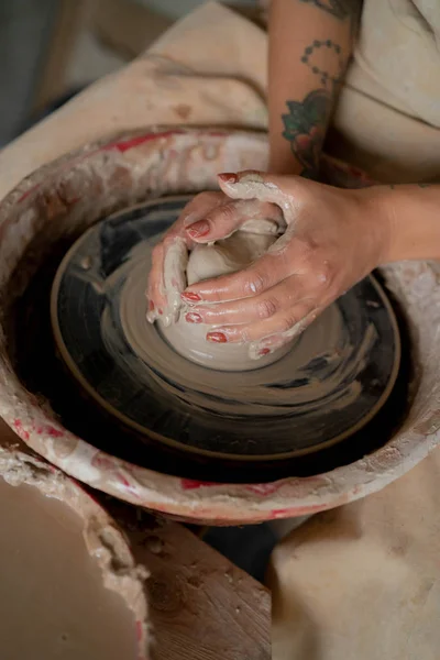 Close-up view of woman hands working on pottery wheel and making clay pot. Hands sculpts a cup from clay pot. Workshop on modeling on the potter\'s wheel.
