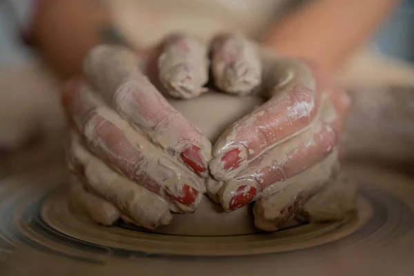 Close-up view of woman hands working on pottery wheel and making clay pot. Hands sculpts a cup from clay pot. Workshop on modeling on the potter\'s wheel.