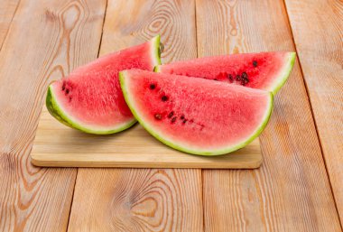 Tahta bir masada kırmızı olgun karpuz dilimleri. 