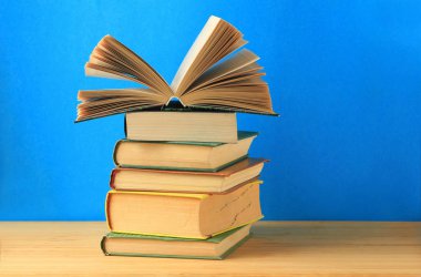 Masanın üzerinde mavi bir arkaplan üzerinde bir kitap yığını. Boşluğu kopyala.