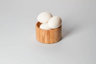 Beyaz arka planda ahşap bir tabakta beyaz tavuk yumurtaları.