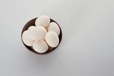 Beyaz arka planda bir tabakta beyaz tavuk yumurtası. Yukarıdan görüntüle.