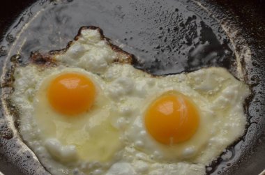 Fotoğraf, sade bir tavada kızartılmış iki yumurtalı bir yumurta gösteriyor..