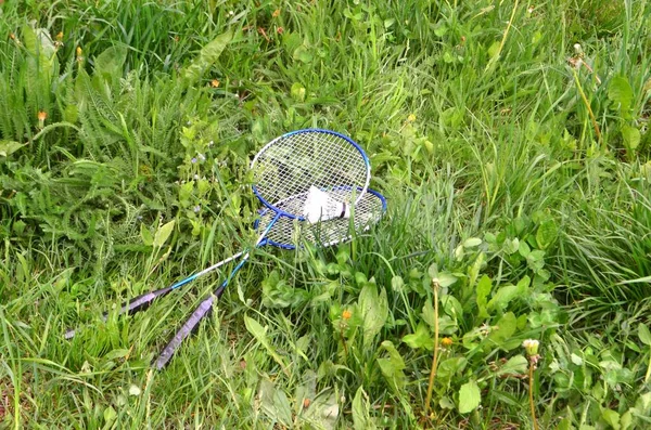 Ended games and rackets along with a shuttlecock, thrown into the spring, green grass.