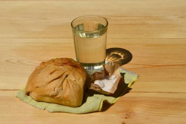 The photo shows home-baked bread, water and salt that lie on a wooden table. clipart