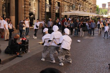 Milan, İtalya - 16 Nisan 2017: Aşçı kostümlü bir sokak sanatçısı şehir merkezindeki Via Dante caddesinde aşçı kuklalarıyla dans ediyor.