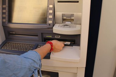 Bir kadın ATM 'den para çekiyor, sağ kolunu ve elini gösteriyor..