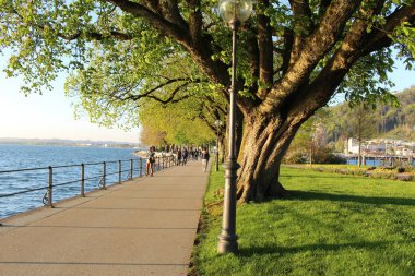 Bregenz, Vorarlberg, Avusturya - 20 Nisan 2016: İnsanlar gün batımında Constance Gölü (Bodensee) kıyısındaki Strandweg caddesinde geziniyorlar.