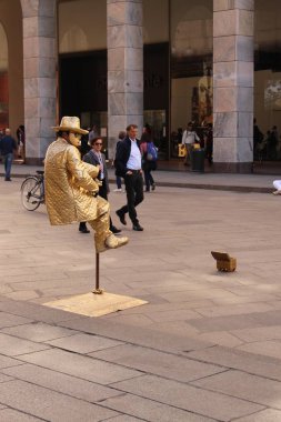Milan, İtalya - 16 Nisan 2017: Altın kostümlü maskeli bir sokak sanatçısı Piazza del Duomo Meydanı 'nda havada asılı duran bir heykel gibi davranıyor.