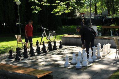 Bregenz, Vorarlberg, Avusturya - 4 Haziran 2017: Constance Gölü kıyısındaki Strandweg Caddesi yakınlarındaki gerçek boyutlarda olan siyah beyaz açık hava satranç tahtasında iki adam satranç oynuyor.