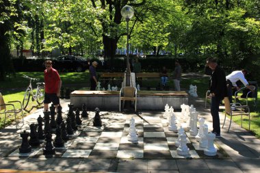 Bregenz, Vorarlberg, Avusturya - 4 Haziran 2017: Constance Gölü kıyısındaki Strandweg Caddesi yakınlarındaki gerçek boyutlarda olan siyah beyaz açık hava satranç tahtasında iki adam satranç oynuyor.