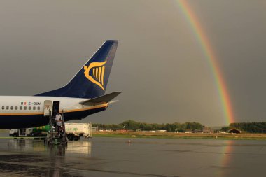 Memmingen, Almanya - 24 Temmuz 2017: Yağmurlu bir günde Allgau havaalanında gerçek bir gökkuşağı arka planına sahip Ryan Air uçağından inen yolcular.