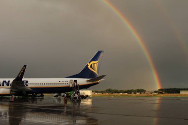 Memmingen, Almanya - 24 Temmuz 2017: Yağmurlu bir günde Allgau havaalanında gerçek bir gökkuşağı arka planına sahip Ryan Air uçağından inen yolcular.