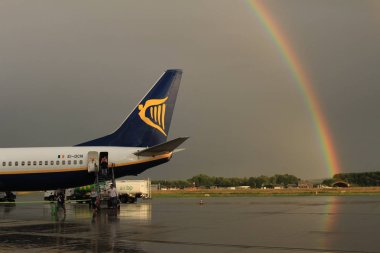 Memmingen, Almanya - 24 Temmuz 2017: Yağmurlu bir günde Allgau havaalanında gerçek bir gökkuşağı arka planına sahip Ryan Air uçağından inen yolcular.