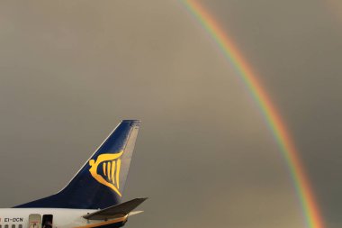 Memmingen, Almanya - 24 Temmuz 2017: Yağmurlu bir günde Allgau havaalanında gerçek bir gökkuşağı arka planına sahip Ryan Air uçağından inen yolcular.