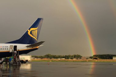 Memmingen, Almanya - 24 Temmuz 2017: Yağmurlu bir günde Allgau havaalanında gerçek bir gökkuşağı arka planına sahip Ryan Air uçağından inen yolcular.