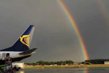 Memmingen, Almanya - 24 Temmuz 2017: Yağmurlu bir günde Allgau havaalanında gerçek bir gökkuşağı arka planına sahip Ryan Air uçağından inen yolcular.