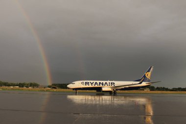 Memmingen, Almanya - 24 Temmuz 2017: Yağmurlu bir günde Allgau havaalanında gerçek bir gökkuşağı arka planına sahip Ryan Air uçağı yeni indi.
