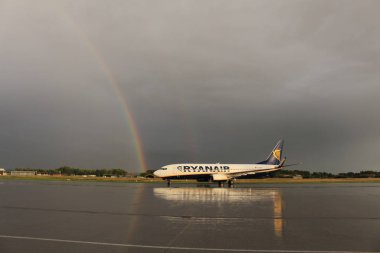 Memmingen, Almanya - 24 Temmuz 2017: Yağmurlu bir günde Allgau havaalanında gerçek bir gökkuşağı arka planına sahip Ryan Air uçağı yeni indi.