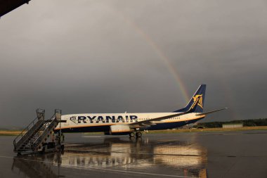 Memmingen, Almanya - 24 Temmuz 2017: Yağmurlu bir günde Allgau havaalanında gerçek bir gökkuşağı arka planına sahip Ryan Air uçağı yeni indi.