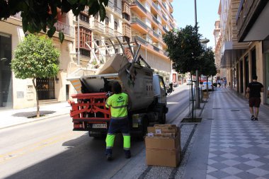 Granada, Endülüs, İspanya - 28 Temmuz 2017: Bir çöpçü karton kutuları toplayıp yazın Calle Recogidas Caddesi 'ndeki kamyona atıyor.