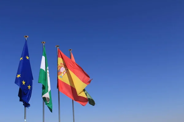 Fluttering flags of European Union, Andalusia, Spain and Granada on top of Watch Tower (Torre de la Vela) of Alcazaba fortress at the historical Alhambra Palace complex in Granada, Andalusia, Spain.