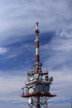 Telecommunication tower with television transmitter antennas on blue sky background
