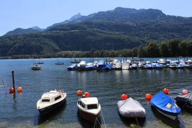 WEESEN, ST. GALLEN, SWITZERLAND - AUGUST 9, 2018: Docked and anchored boats at beautiful Walensee Lake in Weesen harbour located in between Alp mountains. 