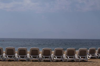 Empty sunbeds lined up in a row at the shoreline of Aegean Sea in Izmir, Turkey.