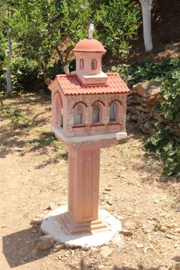 CHANIA, CRETE ISLAND, GREECE - JULY 28, 2016: A miniature church as a garden decoration at the Botanical Park and Gardens Crete.  clipart